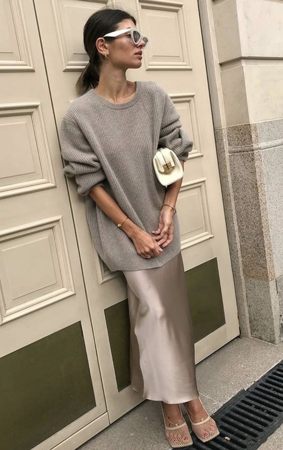 a chic grey fall outfit with an oversized sweater, a slip maxi skirt, white shoes and a small white clutch