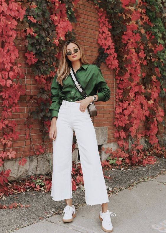 a green satin shirt, white cropped straight jeans, white sneakers and a grey bag for a comfy fall work look