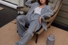 04 a simple and chic fall work look with a grey pantsuit with an oversized blazer, a white top, trainers and a bucket bag