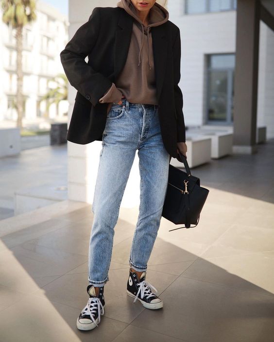 a relaxed and cozy fall work outfit with a taupe hoodie, a black blazer, light blue jeans, black high top sneakers and a black tote