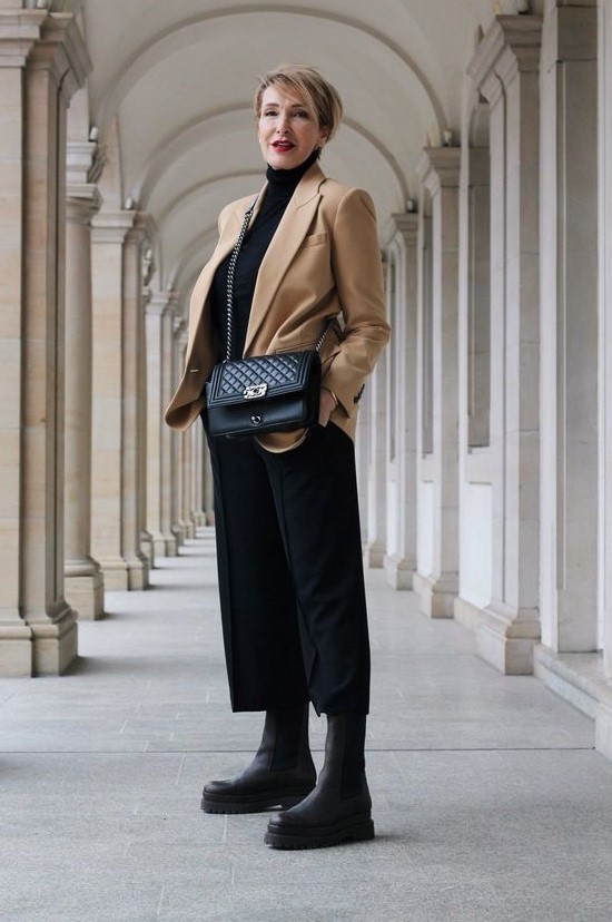 a bold and contrasting look with a black turtleneck, culottes, chunky boots, a bag and a beige blazer is amazing