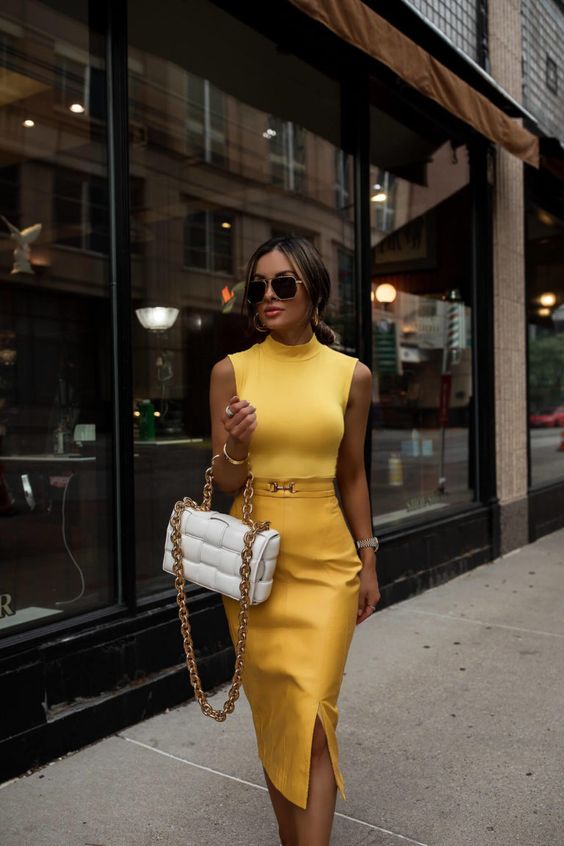 a bold and refined fall work outfit with a yellow sleeveless top, a matching pencil skirt with a slit and a white bag with chain
