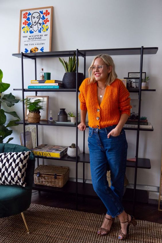 a cute office look with an orange cardigan tucked into blue jeans, leopard shoes and layered necklaces