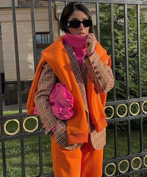 a bright fall outfit with a pink jumper and a clutch, a plaid blazer, an orange sweatshirt, orange leather pants