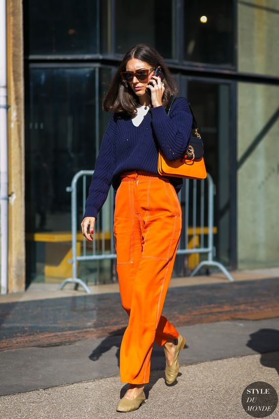 a catchy fall outfit with a white t shirt, a navy sweater, orange pants, a two tone bag and nude shoes