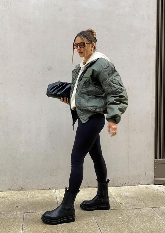 a white hoodie, black leggings, a green cropped bomber jacket, black chunky boots and a black clutch