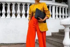 20 a bright and statement work outfit with a mustard top and a matching oversized blazer, hot red pants, a black clutch is wow