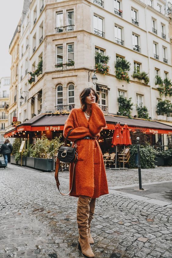 an orange sweater dress with pockets, a black belt, tan suede boots and a small black bag with chic details