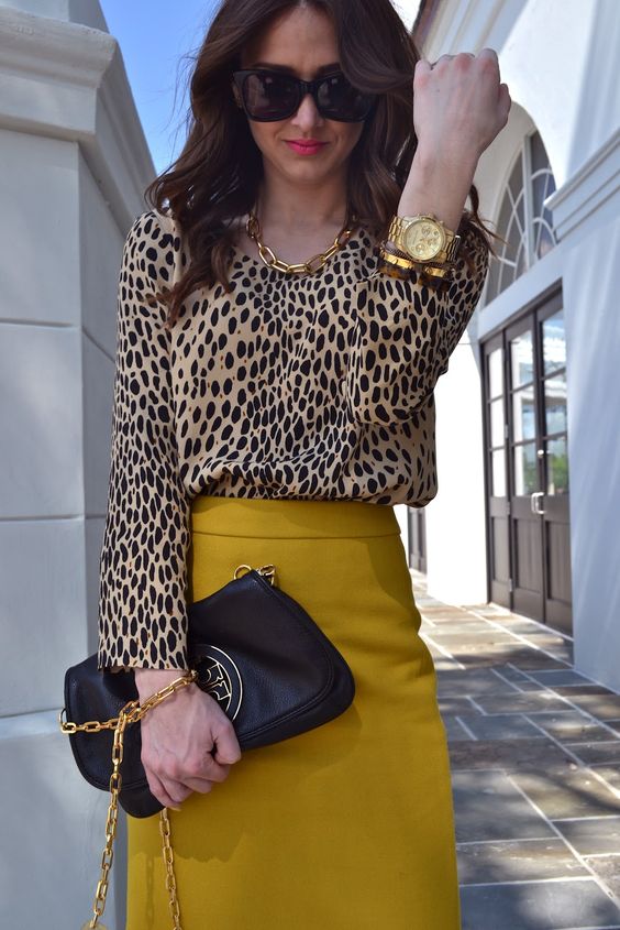 a refined fall outfit with a leopard print top, a mustard pencil skirt, a chain necklace, a black bag with chain and a bracelet with a watch