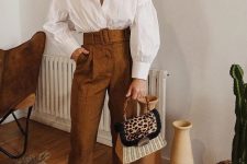 24 a white oversized shirt with pleated sleeves, rust-colored high waisted pants, floral print shoes and a woven bag with a leopard print