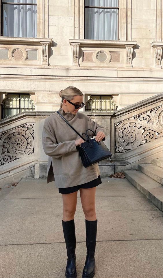 a beige oversized sweater, black shorts, black knee chunky boots and a black bag for chilly fall days