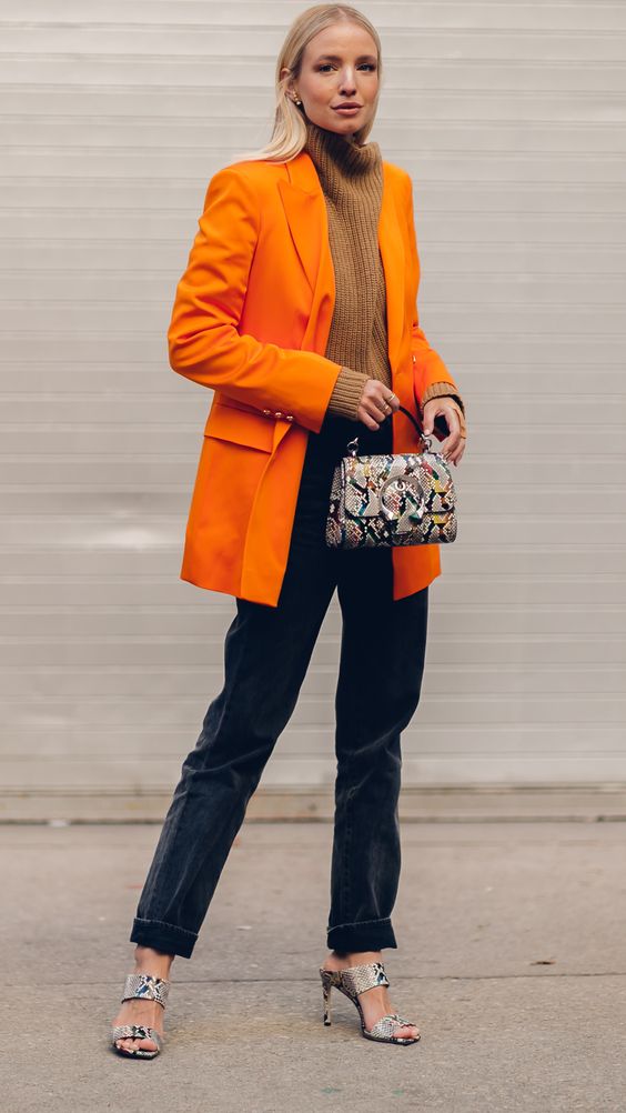 a brown jumper, an orange oversized blazer, black velvet pants, snakeskin shoes and a matching bag