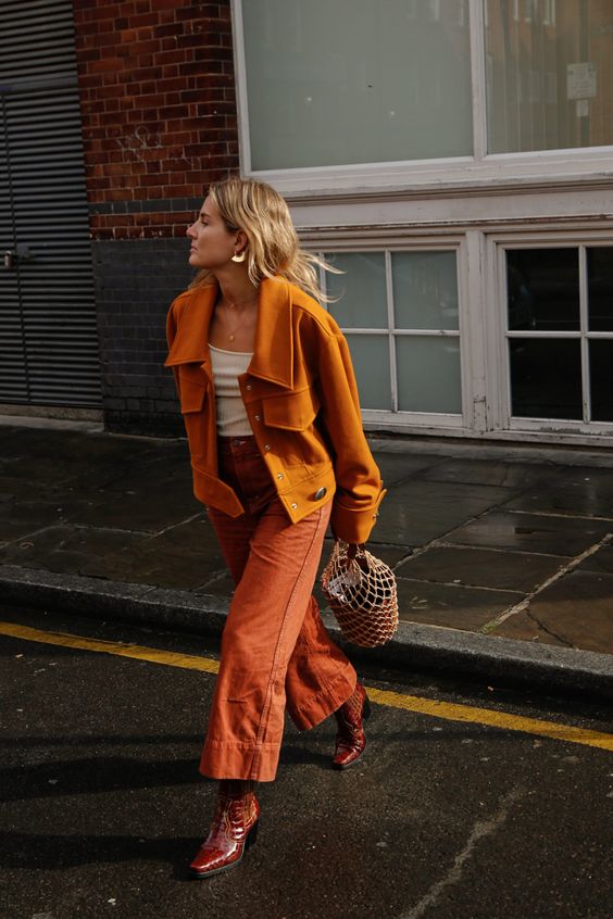 a chic and bold fall look with an orange shirt jacket, a white top, burnt orange trousers, burgundy boots and a bucket bag