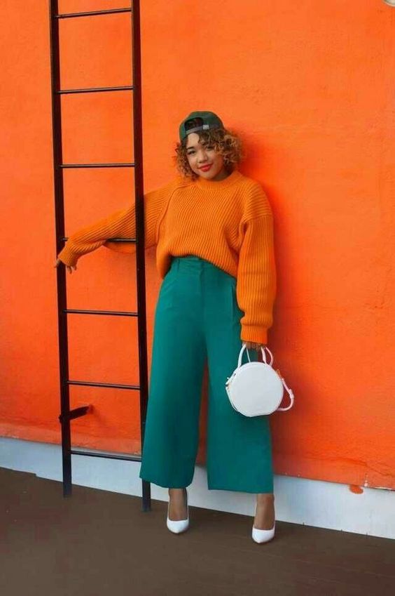  a bold and cool fall work look with an orange chunky knit sweater, teal cropped wideleg pants, white shoes and a white round bag