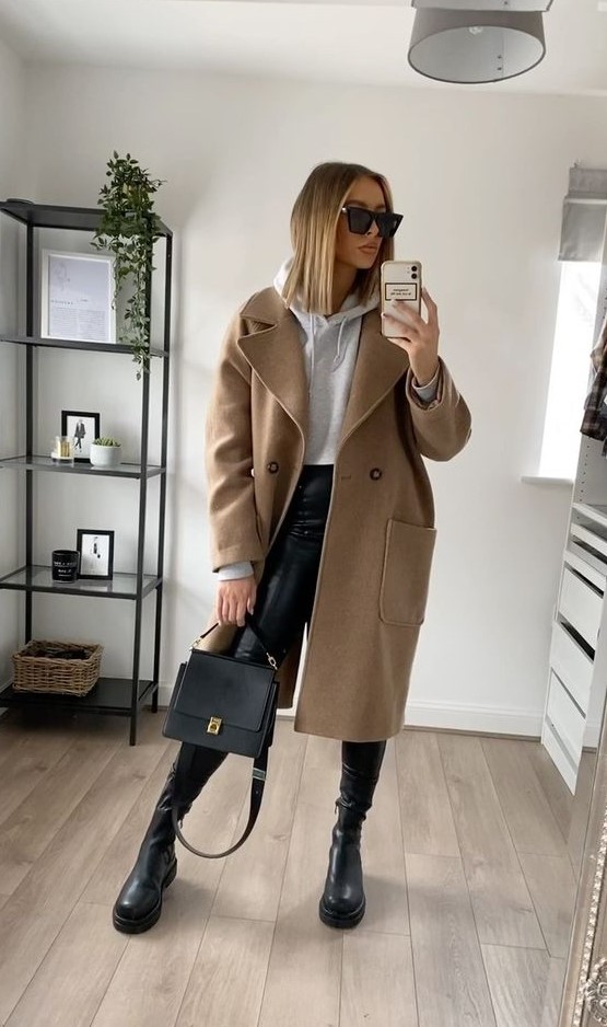 an everyday outfit with a grey hoodie, leather leggings, boots, a tan midi coat, a black bag for the fall