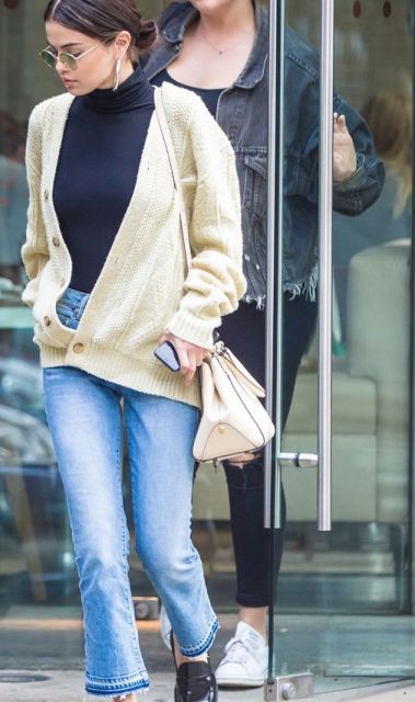 With silver earrings, rounded sunglasses, beige leather tote bag, blue cropped flare jeans and black patent leather flat shoes