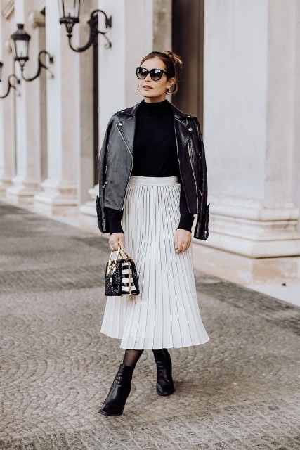 With sunglasses, golden earrings, white high-waisted pleated midi skirt, black and white mini bag and black patent leather ankle boots