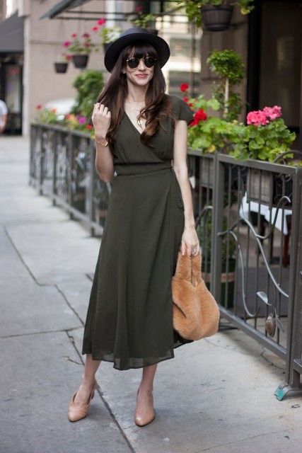 With wide brim hat, rounded sunglasses, olive green short sleeved wrap midi dress and beige low heeled shoes