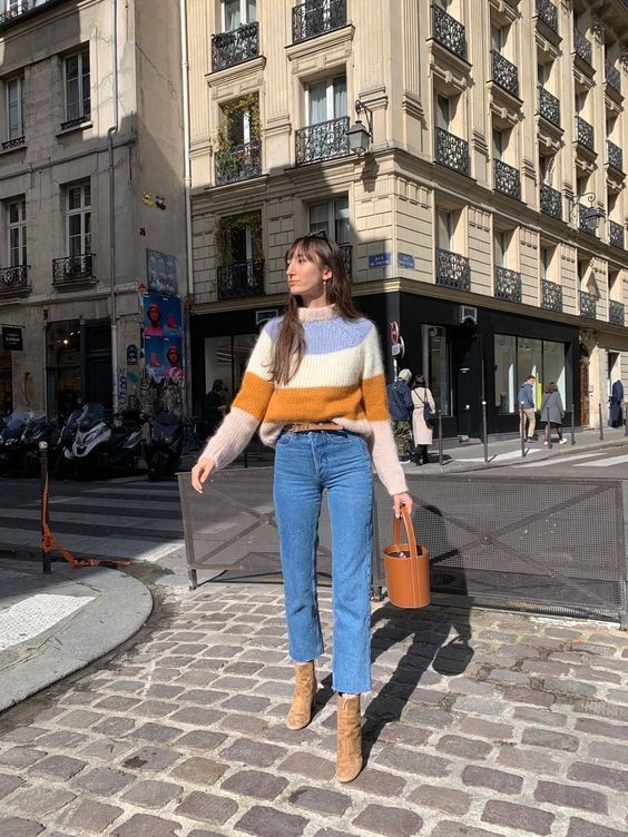 a bright striped sweater, blue cropped jeans, tan boots, a brown bucket bag and a brown belt for Paris chic