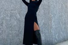 a chic and simple fall outfit with a black midi sweater dress and a thigh high slit, black over the knee boots and a small bag