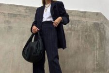 a chic black thin stripe pantsuit, a white t-shirt, layered necklaces, white platform sneakers and a black bag