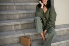 a classy fall work look with a green chunky knit cardigan, green jeans, brown shoes and a beige box bag
