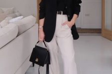 a classy monochromatic work outfit with a black t-shirt, creamy high waisted pants, white sneakers, an oversized black blazer and a black bag