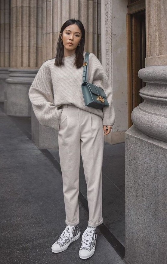 a comfy grey outfit with an oversized sweater, trousers, sneakers and a green bag for a color accent
