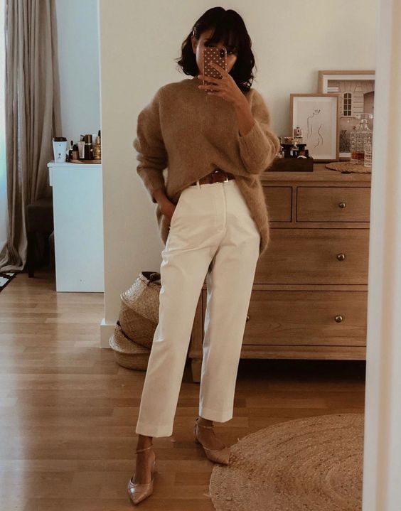 a cozy fall outfit with a beige oversized sweater, white trousers, a brown belt and nude ankle strap shoes
