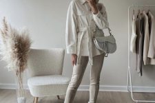 a creamy shirtjacket, off-white leather leggings, nude Chelsea boots, a creamy hat and a white saddle bag