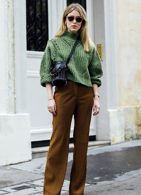 a fall outfit with a green chunky knit sweater, brown pants, a black bucket bag is chic and cozy