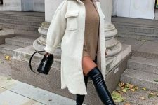 a fall to winter outfit with a beige turtleneck dress, black over the knee boots, a creamy shirt coat and a black bag