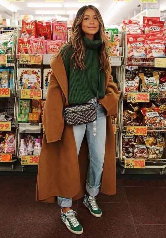 a lovely fall outfit with a green turtleneck sweater, blue jeans, green sneakers, a brown coat and a black printed bag