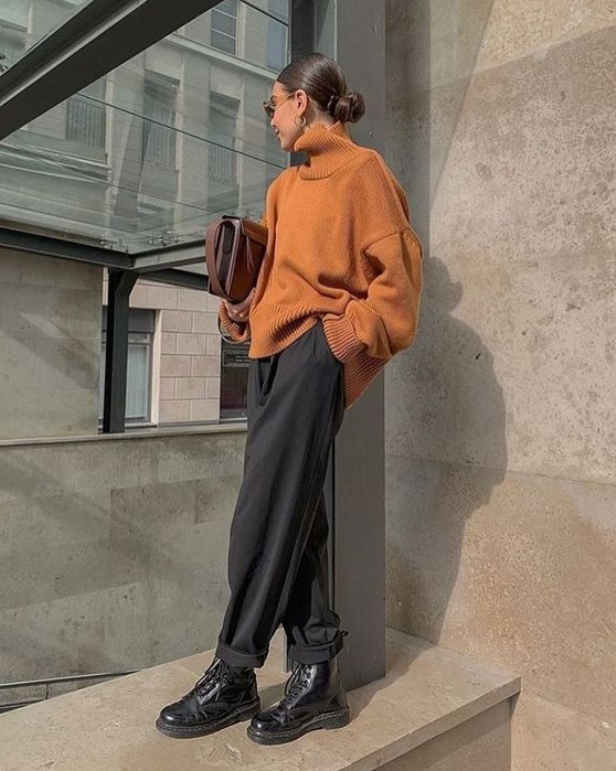 a minimalist look with a touch of bright color, an orange oversized sweater, black pants, black boots and a brown bag