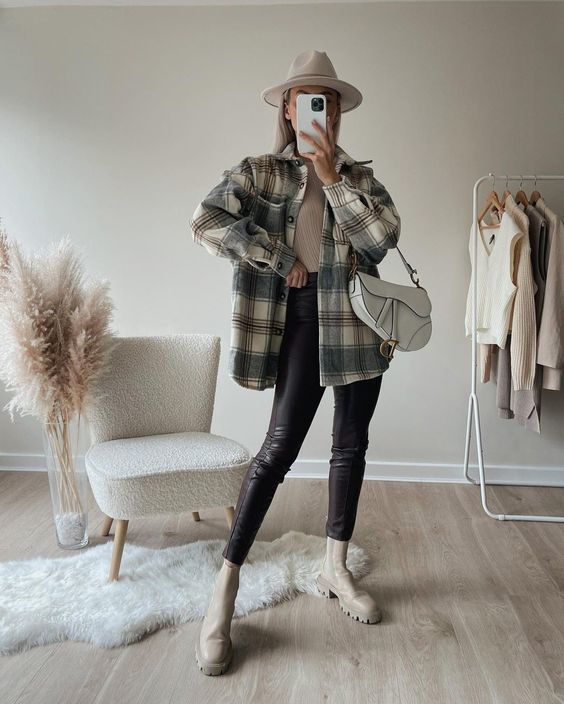 a neutral top, a plaid shirt jacket, black leather pants, creamy Chelsea boots, a creamy hat and a white bag