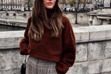 a rust-colored sweater, grey plaid pants, a beige cap and a black bag for a cozy Parisian chic look