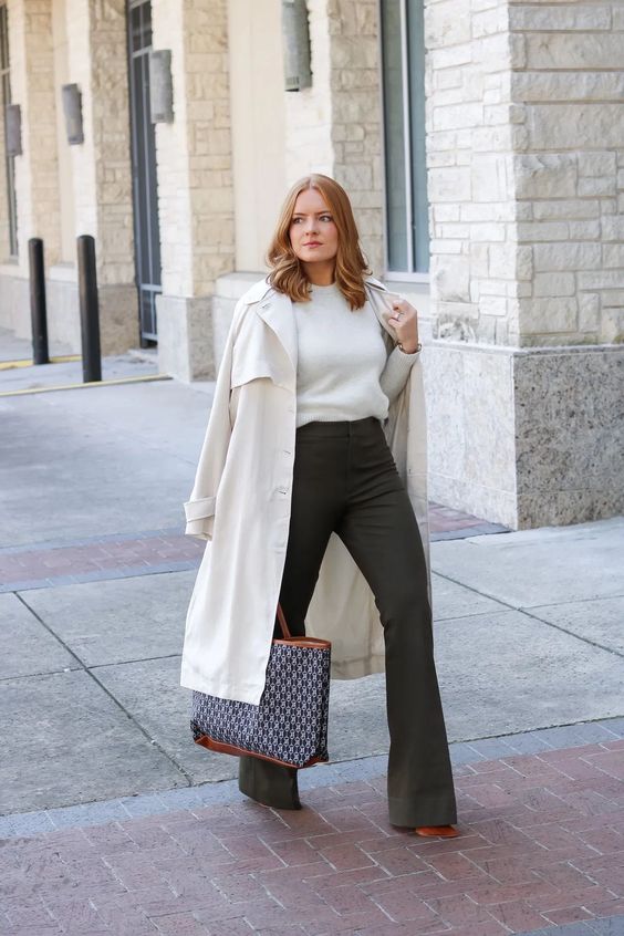 a simple and cool fall work outfit with a white top, dark green flare pants, a creamy trench and a printed tote will always work