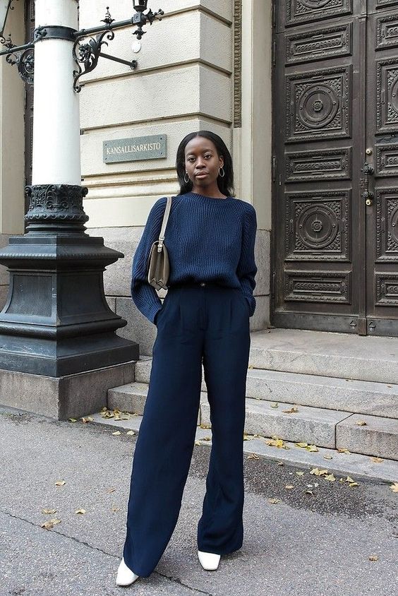 a sophisticated fall work outfit with a navy jumper and matching pants, white boots and a neutral bag