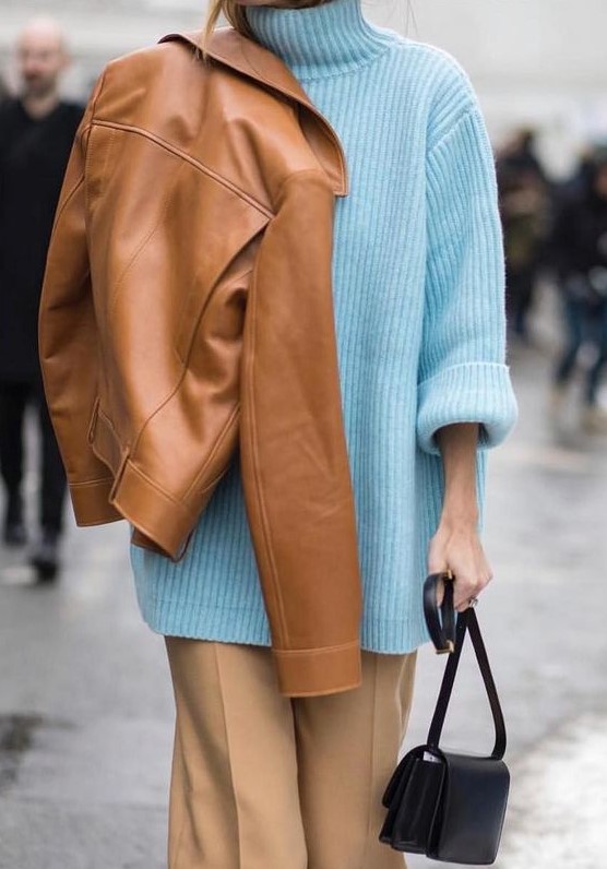 a super oversized light blue turtleneck sweater, beige trousers, a tan leather jacket and a black bag for a statement