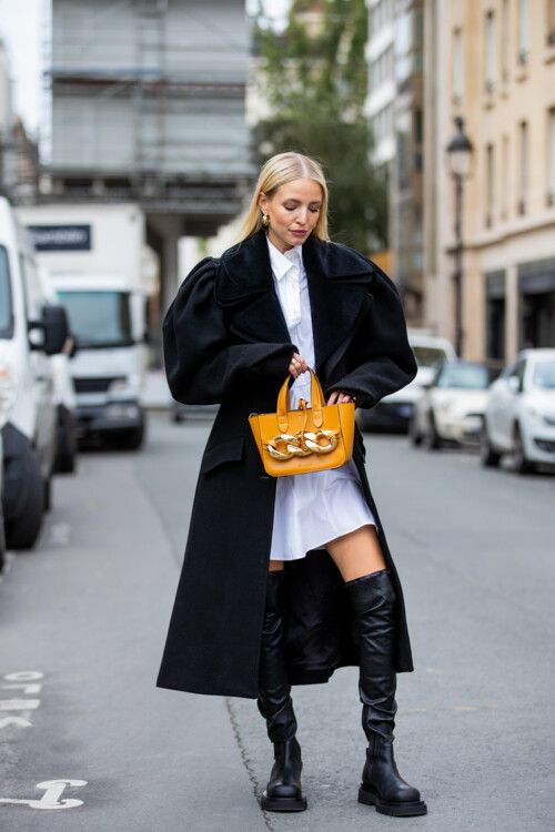 a white shirtdress, black over the knee boots, a black trench with puff sleeves and a whimsical yellow bag with chain