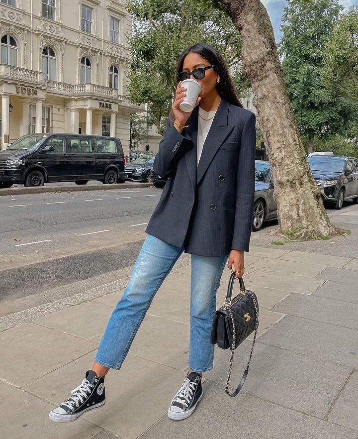 a white t-shirt, blue cropped jeans, a black striped blazer, a black bag and black Converse sneakers for a more relaxed work look
