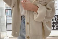 a white t-shirt, light blue jeans, an oversized creamy cardigan with cuffed sleeves for a casual or work outfit