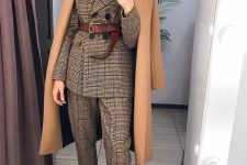 an elegant and formal fall work outfit with a grey plaid pantsuit, a brown belt, burgundy boots, a camel coat