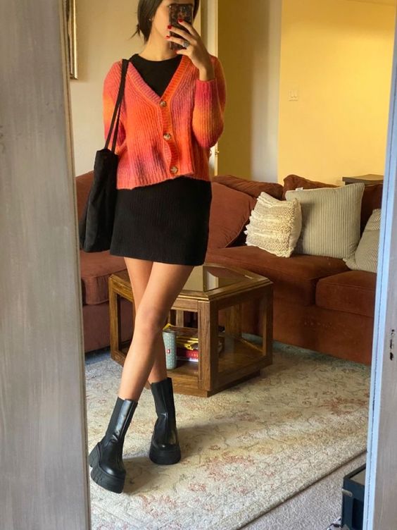 a classy fall look with a black mini dress, chunky boots, a tote bag and an orange cropped cardigan