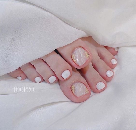 a super delicate pedicure in white and blush with a marble effect and gold foil is a dreamy and lovely solution