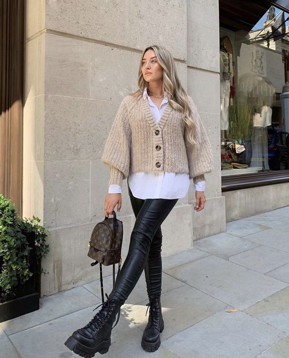 a white oversized shirt, a tan cropped cardigan, black leather leggings and black boots, a backpack