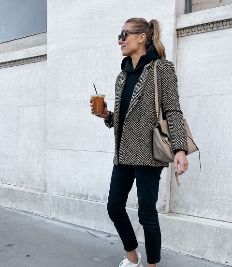 With oversized sunglasses, beige bag, black jeans and white and gray sneakers