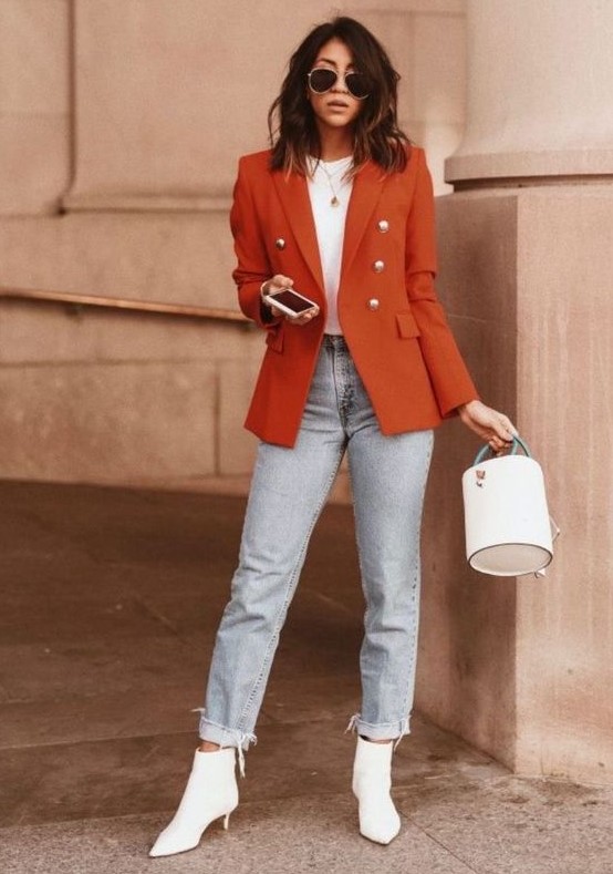 a bright fall outfit with a white t-shirt, light blue jeans, white kitten heel booties, a rust blazer and a white bucket bag