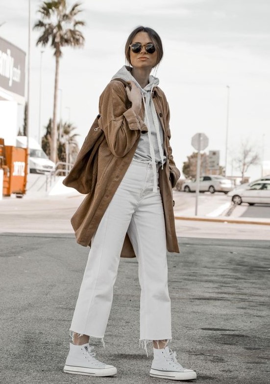 a casual fall outfit with a grey hoodie, white cropped jeans, white sneakers, a beige trench and a matching tote