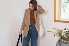 a casual work outfit with a rust-colored turtleneck, a beige plaid blazer, blue mom jeans, white sneakers and a black bag
